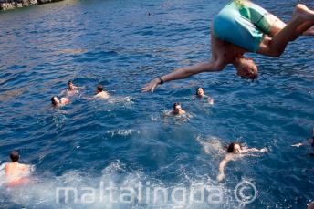 A teenage student doing a front flip into the sea